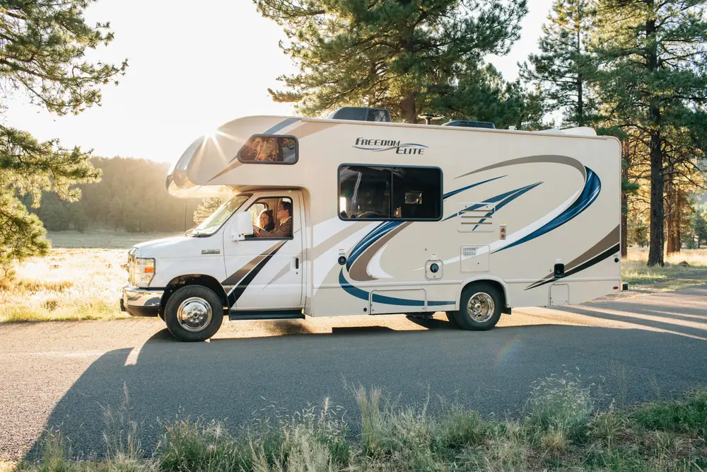 Class C motorhome parked on a forest road at golden hour