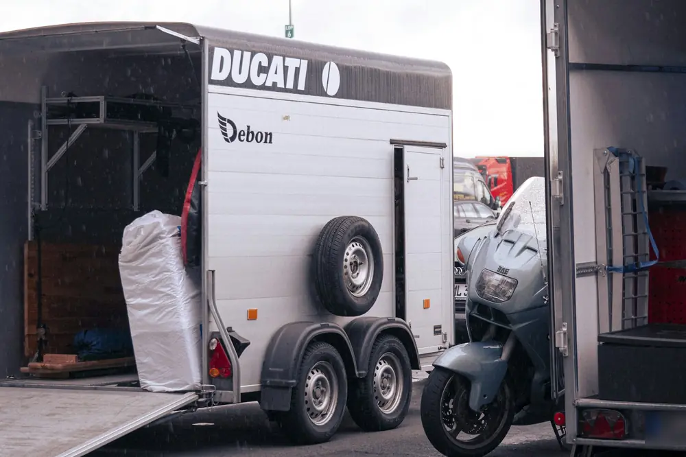 Touring motorcycle next to an enclosed motorcycle trailer with its ramp down